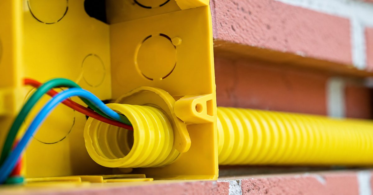 Conduíte corrugado amarelo protegendo fiação elétrica em caixa de passagem